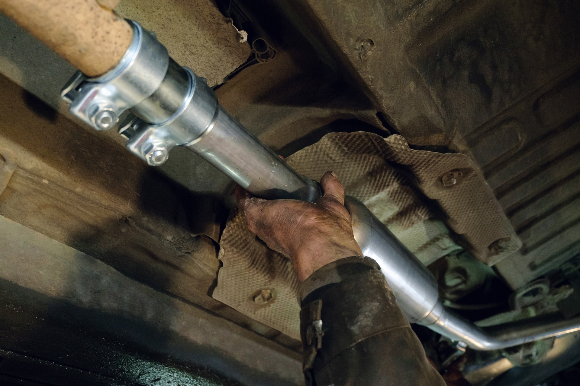 Auto mechanic installs a new car exhaust pipe